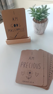 Small wooden sign with 'I am a child of God' text on a white surface with a plant in the background.